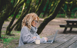 vrouw achter laptop in park